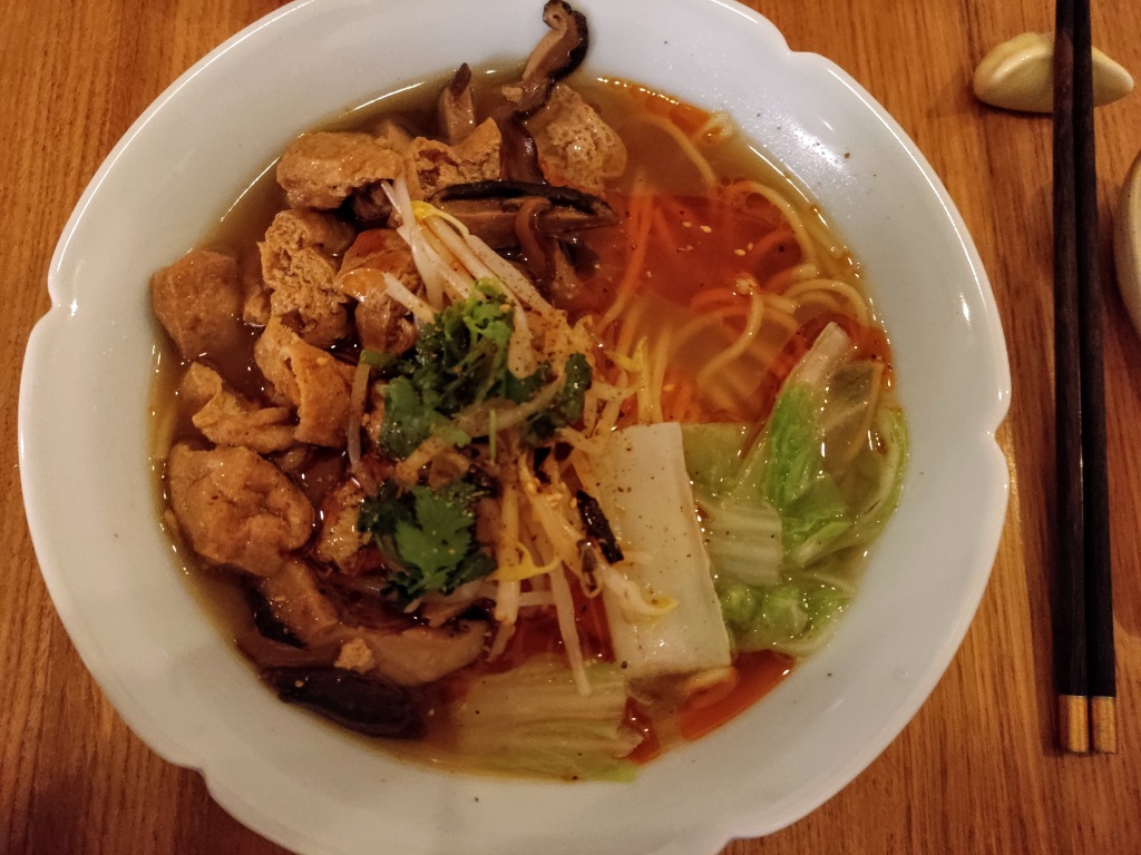 A big bowl filled with broth and noodles topped with tofu and vegetables